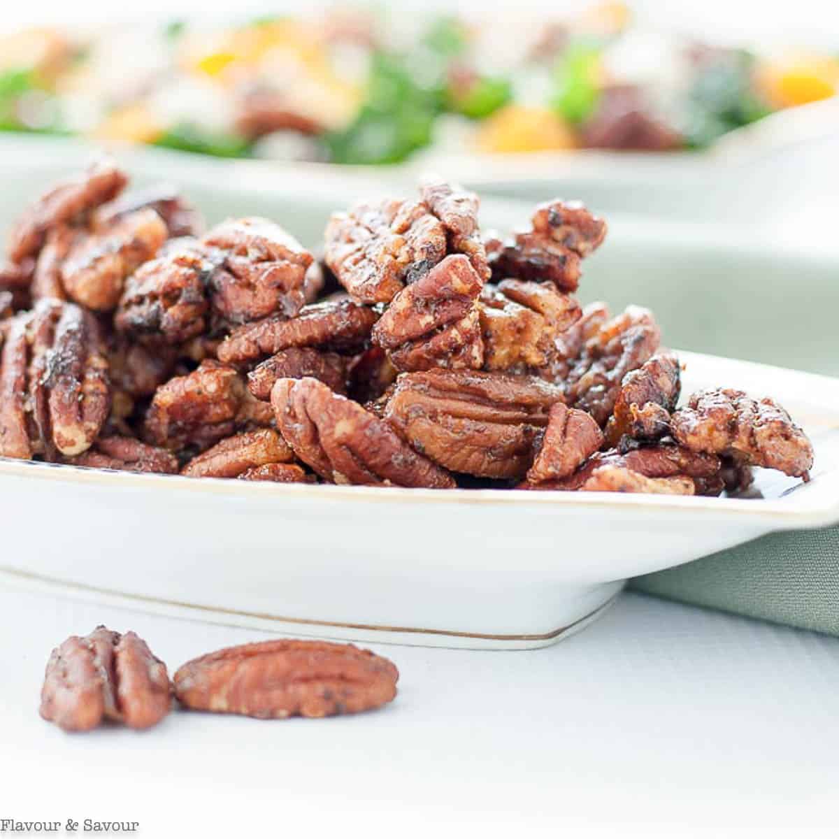 A dish piled high with caramel spiced pecans.