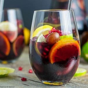 Side view of a glass of Pomegranate Red Wine Sangria with orange, lemon and lime slices