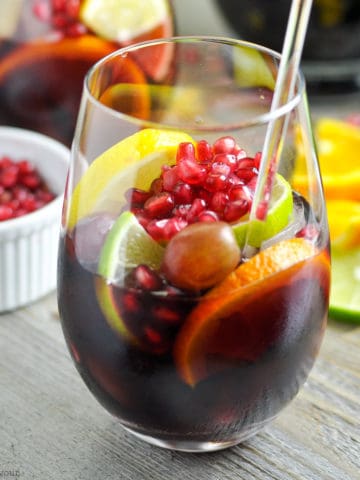 A glass of Pomegranate Sangria with pomegranate arils in the background