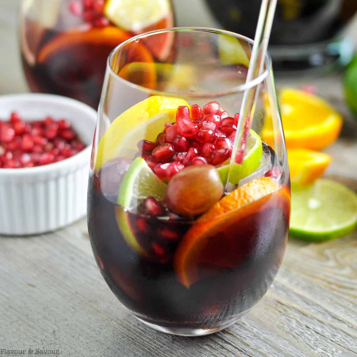 A glass of Pomegranate Sangria with pomegranate arils in the background