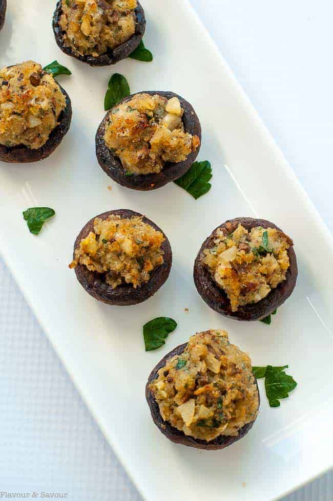 A platter of one bite appetizers including deviled eggs, stuffed mushrooms, and bruschetta with vibrant toppings.