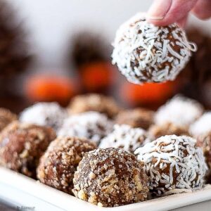 fingers picking up a peanut butter pumpkin energy ball from a plate