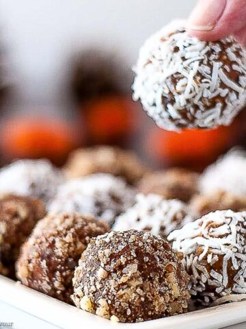 fingers picking up a peanut butter pumpkin energy ball from a plate