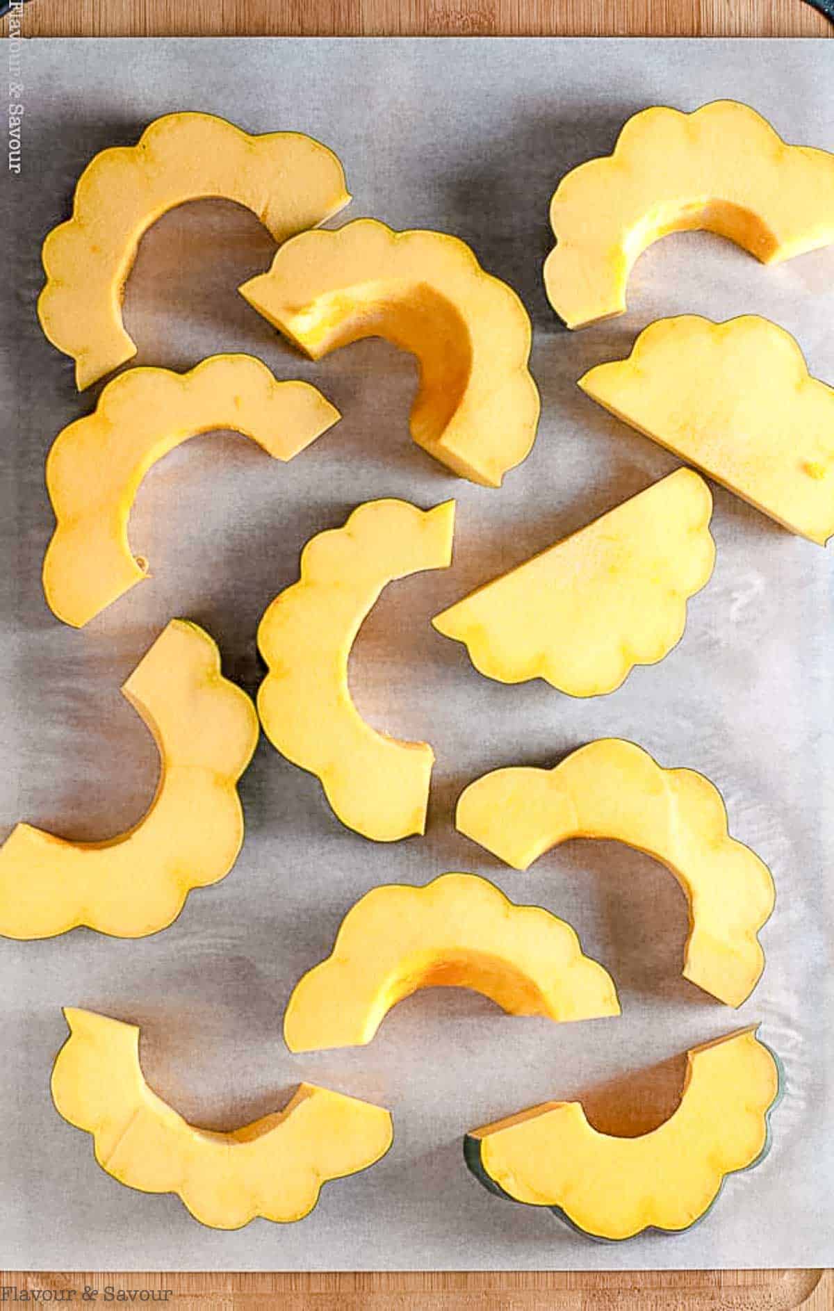 Slices of acorn squash on a baking sheet.