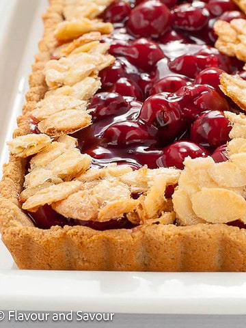 Close-up view of part of a sour cherry almond tart with a gluten-free fluted crust.