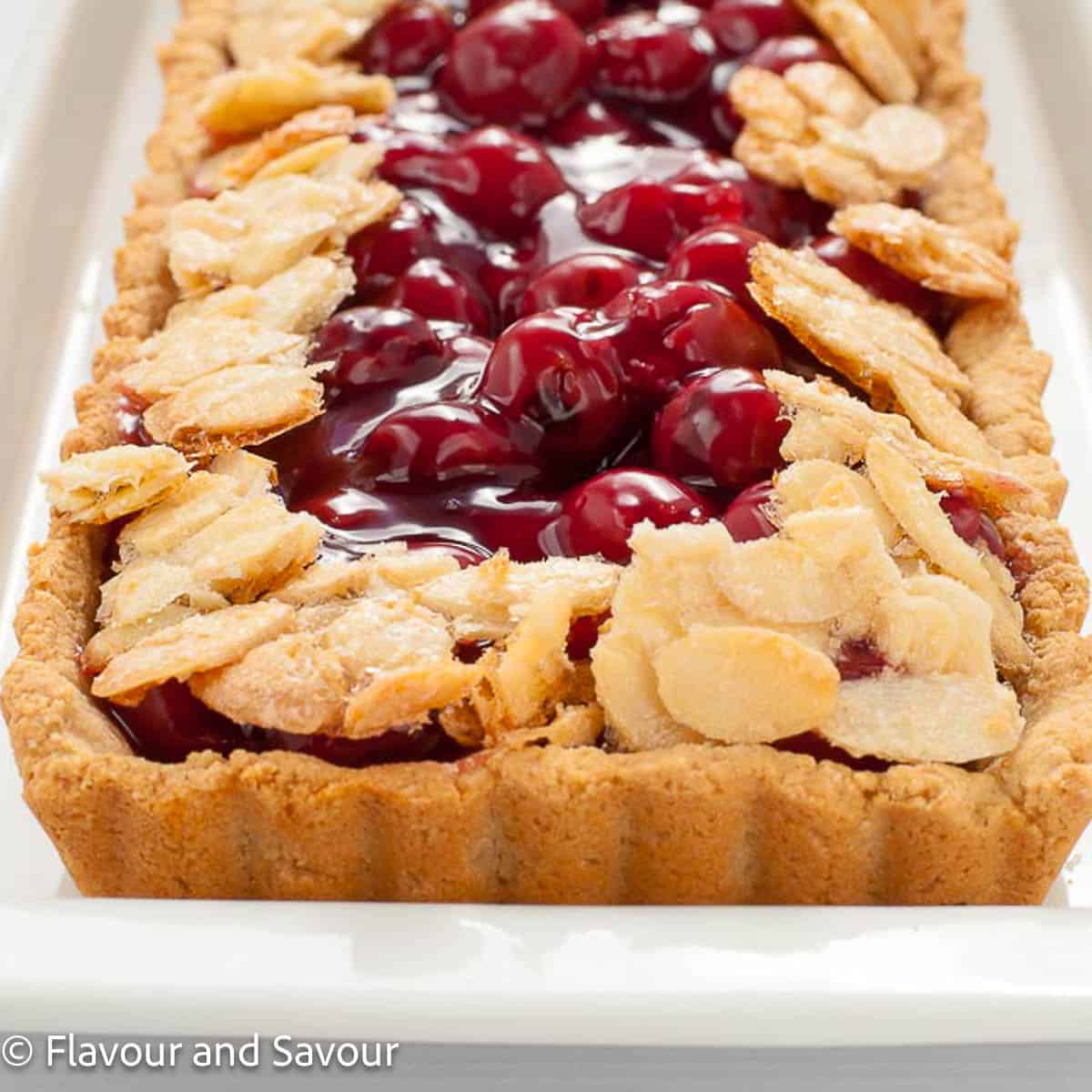 Close-up view of part of a sour cherry almond tart with a gluten-free fluted crust.