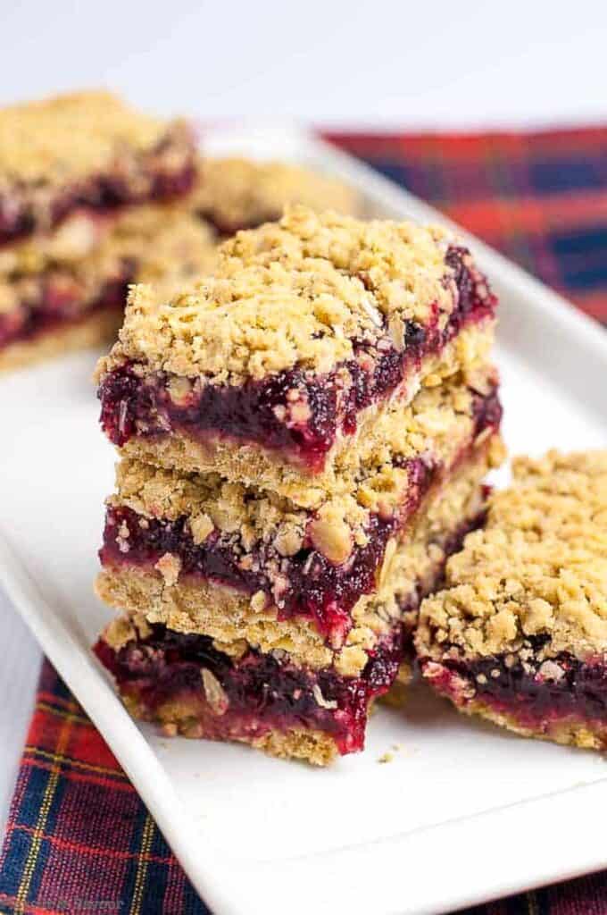 a stack of cranberry lemon oatmeal bars on a white plate