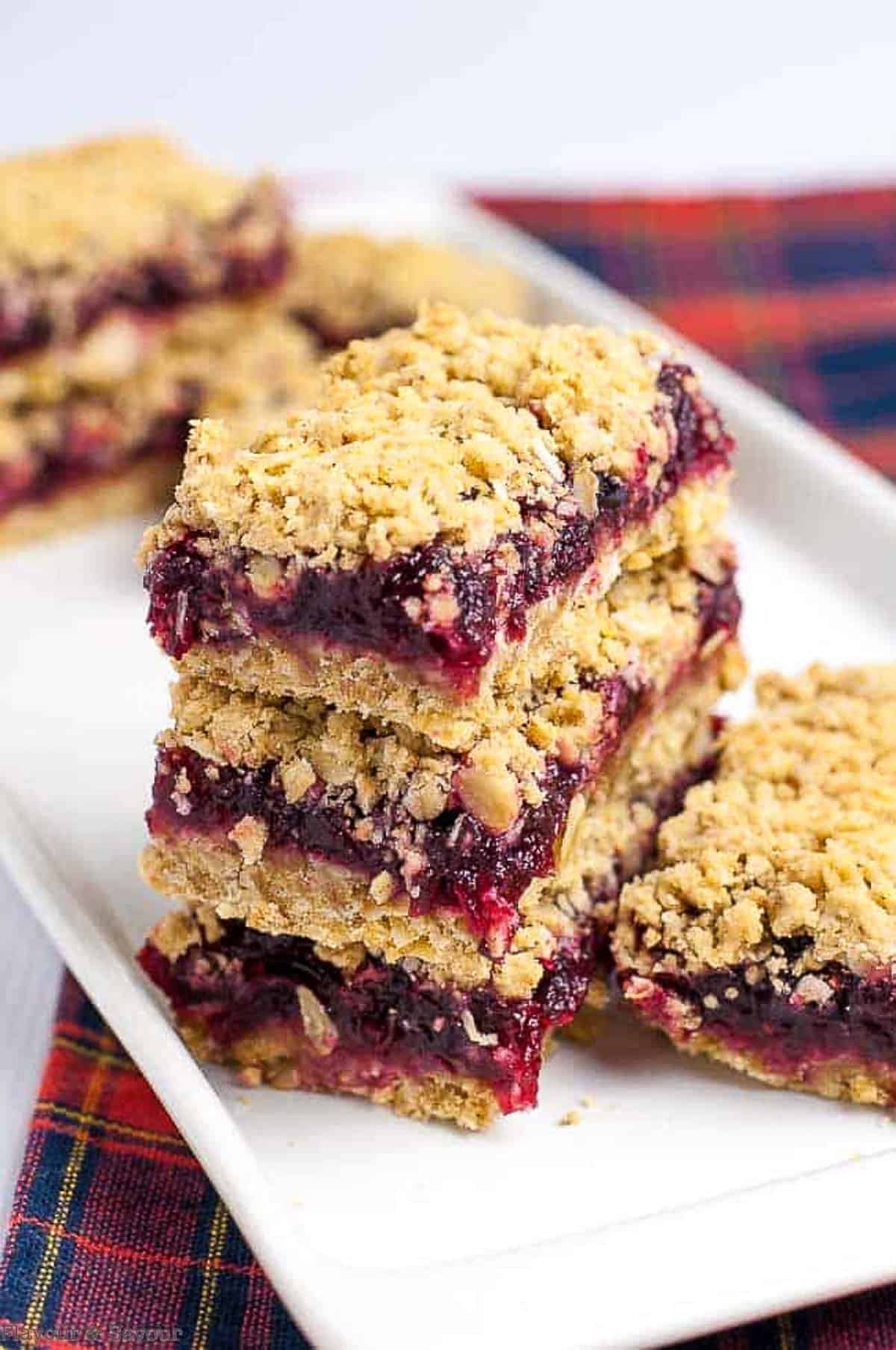 A stack of cranberry lemon oatmeal bars on a white plate.