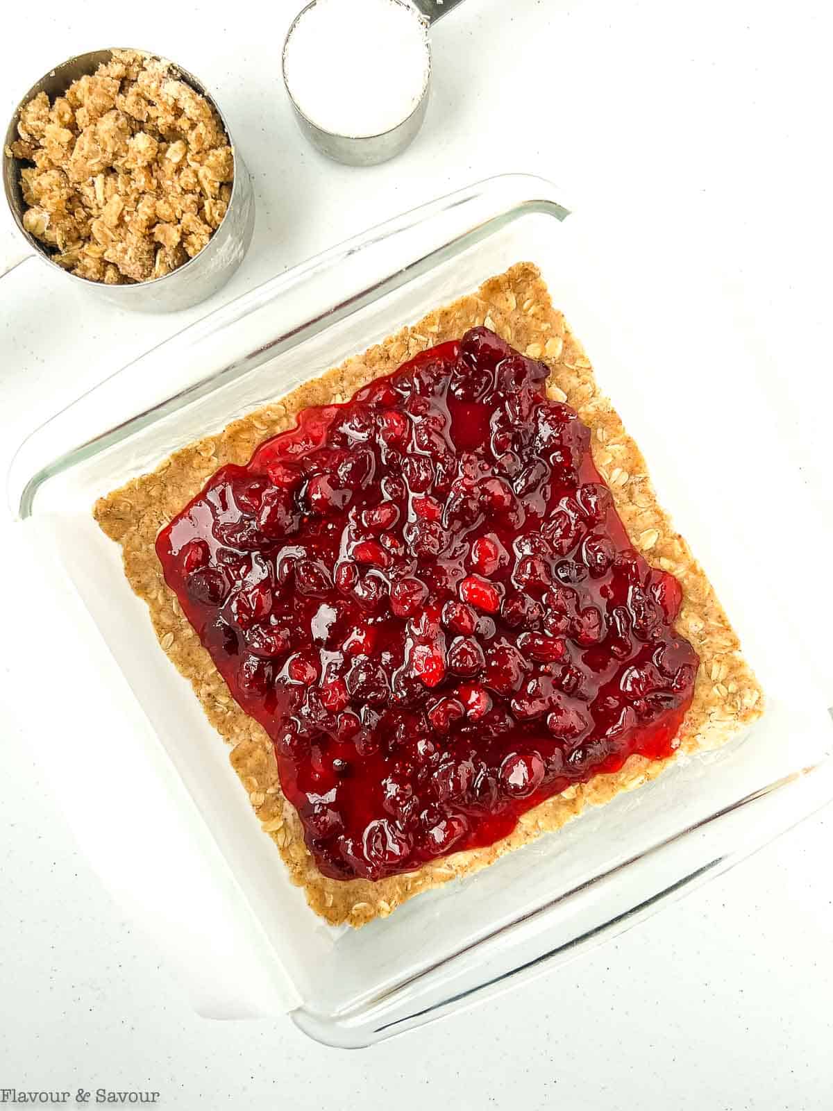 Cranberry filling spread on top of oatmeal base for cranberry bars.