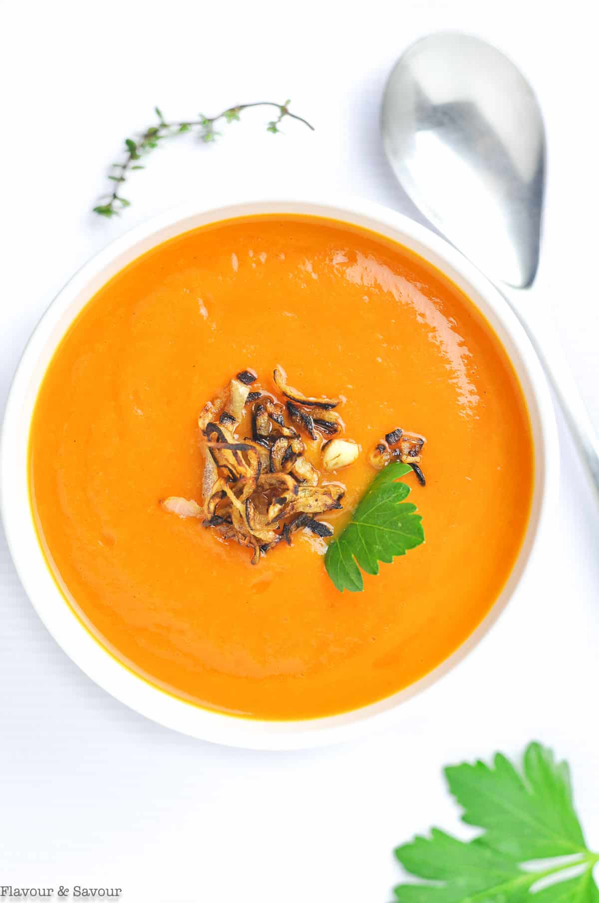 Overhead view of a bowl of carrot ginger soup garnished with crispy fried shallots