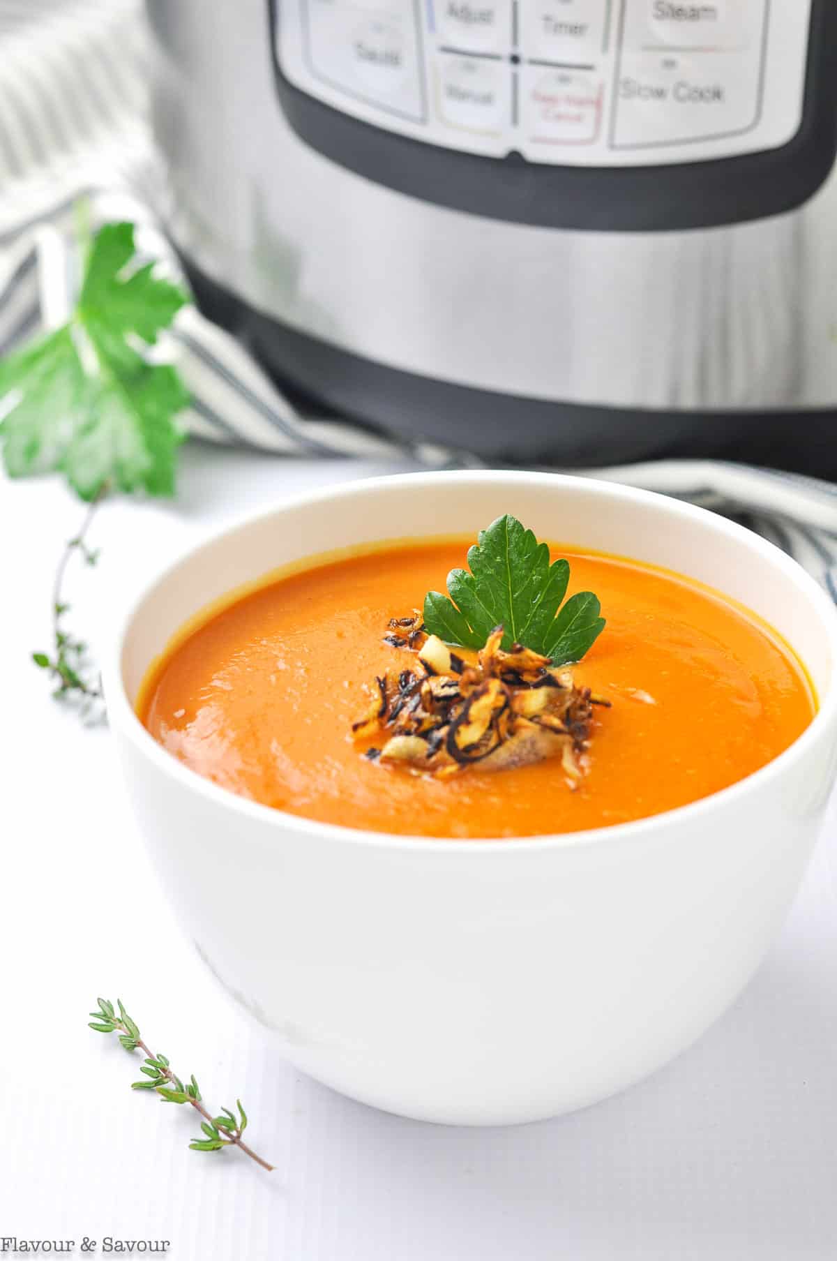 A bowl of Carrot Ginger Soup with garnishes.