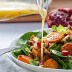 Pouring Dressing on Roasted Sweet Potato Salad with Maple Walnuts and Pomegranate