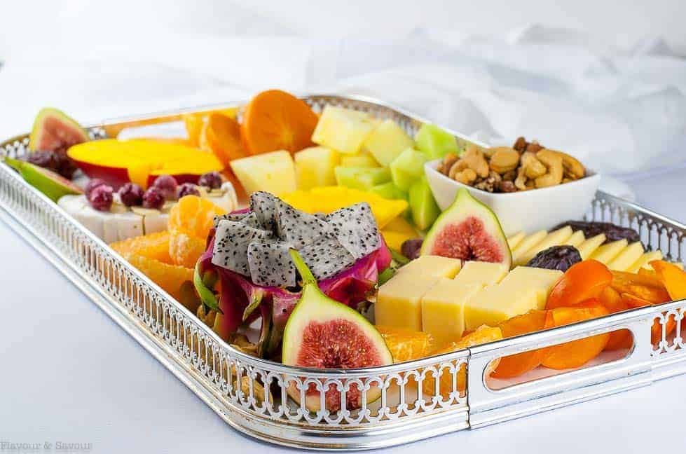 Side view of Tropical Fruit, Nut and Cheese Platter on a rectangular silver tray