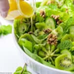 pouring honey-lime vinaigrette on kiwi cuc