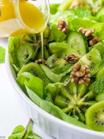 pouring honey-lime vinaigrette on kiwi cuc