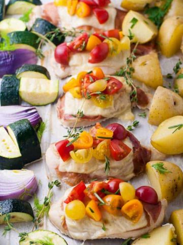 Prosciutto and Cheesy Chicken Sheet Pan Dinner baked on one pan and topped with cherry tomatoes and herbs.