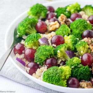 A bowl of broccoli quinoa salad with grapes and walnuts.
