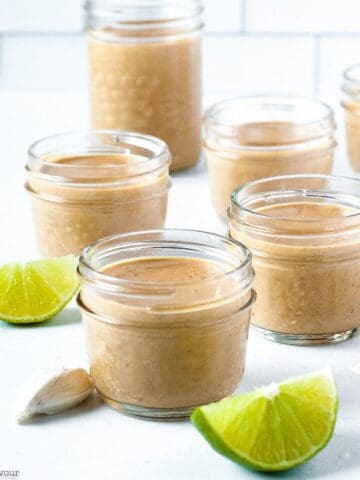 jars of peanut sauce with coconut milk with lime slices on the counter