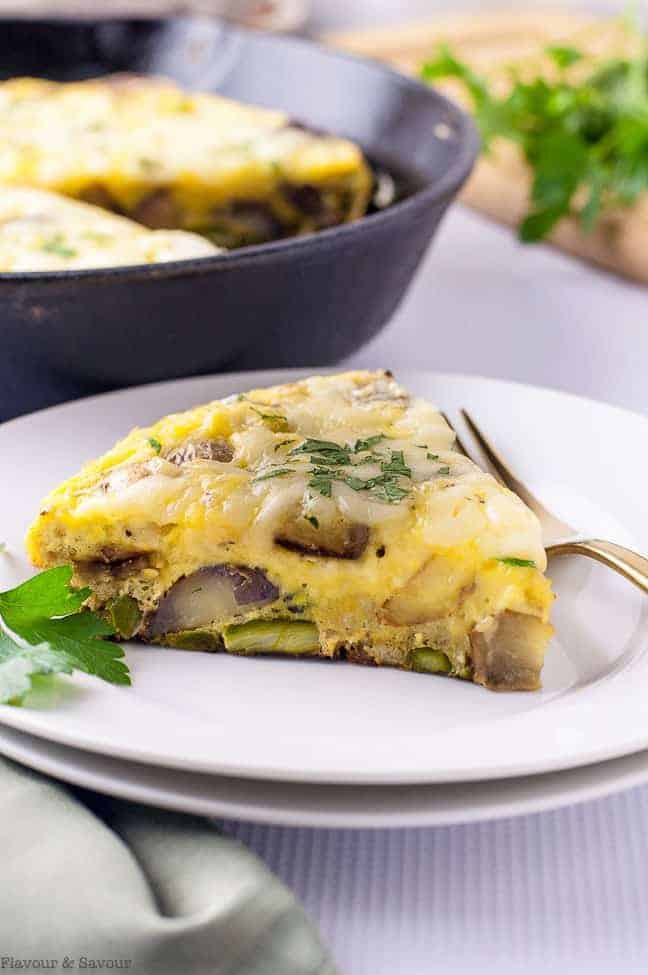 a wedge of Double Cheese Asparagus Leek Frittata on a white plate