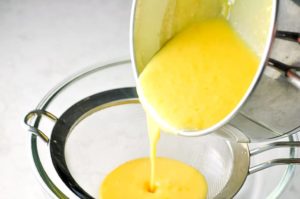 Straining lemon curd through a sieve to make Lemon Curd Tart