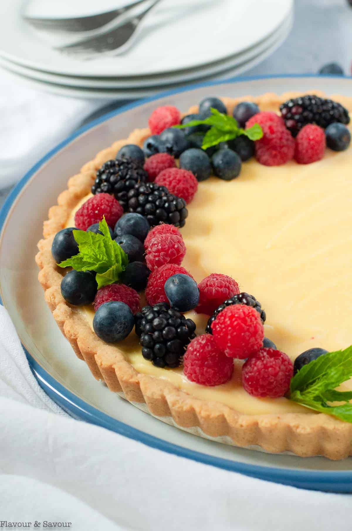 side view of lemon curd tart in a round pan decorated with fresh berries