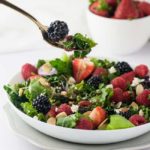 A forkful of Triple Berry Mixed Green Salad with strawberries, blackberries, raspberries, feta cheese and flaked toasted almonds.