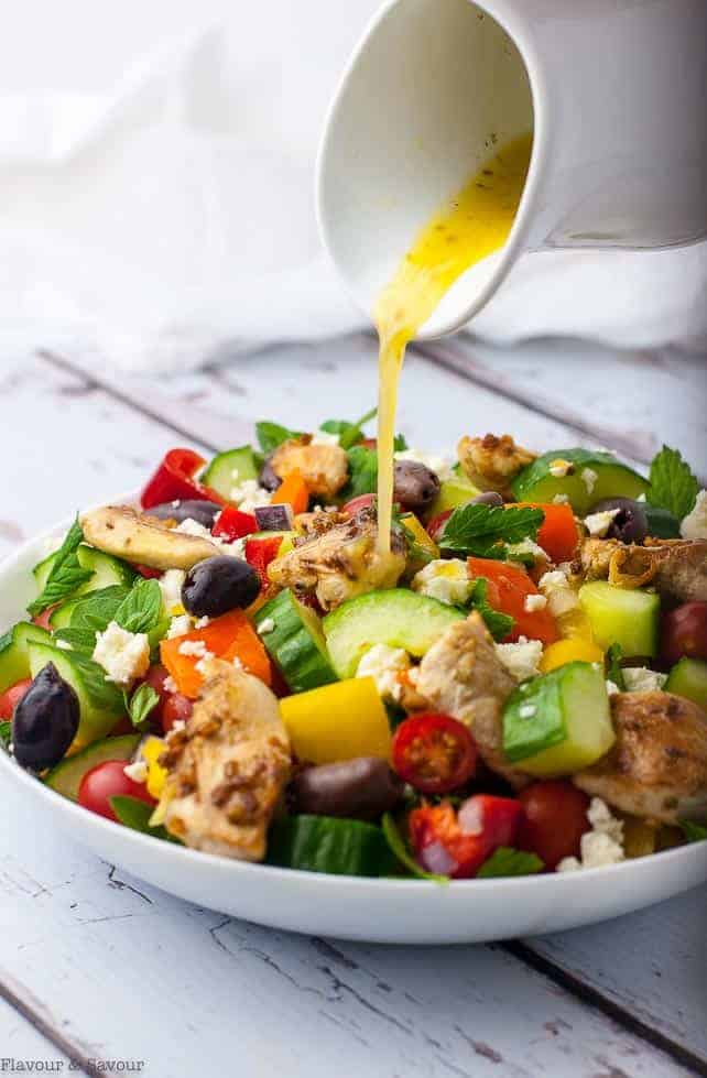 Pouring dressing on Marinated Lemon Chicken Greek Salad with Mint