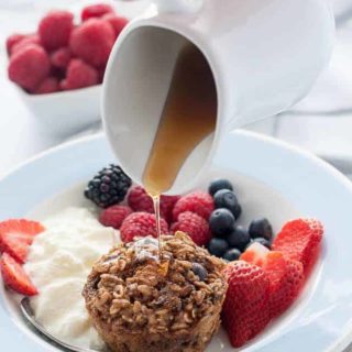 Pouring maple syrup on Mixed Berry Baked Oatmeal Cups with Chia and Kefir.