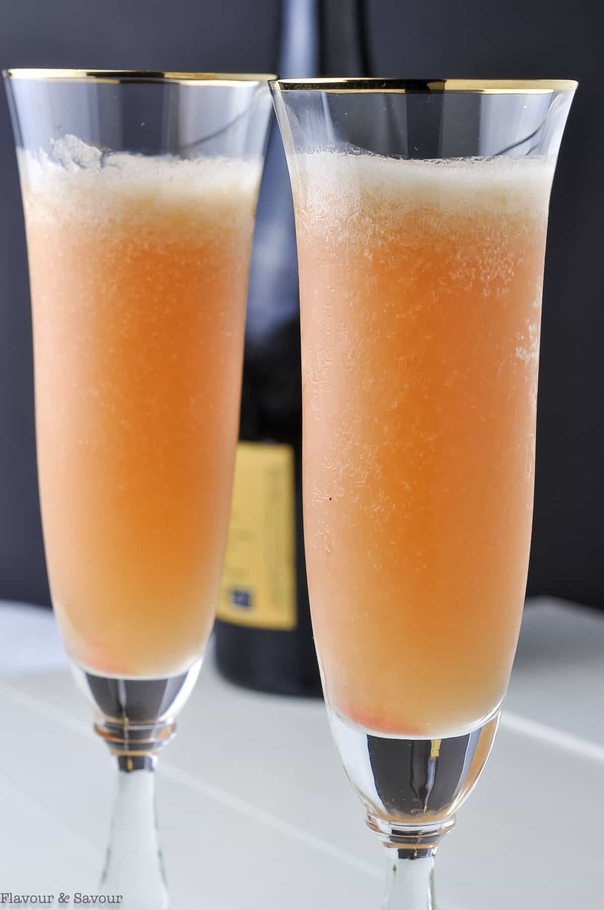 Close up view of two sparkling wine flutes with rhubarb bellini cocktail.