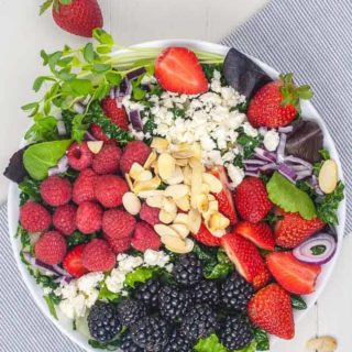 Overhead view of Triple Berry Mixed Green Salad with blackberries, strawberries, raspberries and feta cheese.