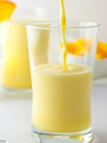 Orange collagen creamsicle smoothie in a glass with a slice of fresh orange.