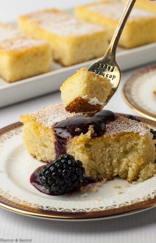 Close up view of a forkful of Flourless Lemon Almond Ricotta Cake with Blackberry Coulis