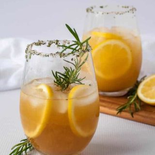 Two glasses of Pineapple Ginger Kombucha Cocktail garnished with a sprig of rosemary