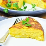 Close up view of a wedge of tortilla española on a plate with a fork.