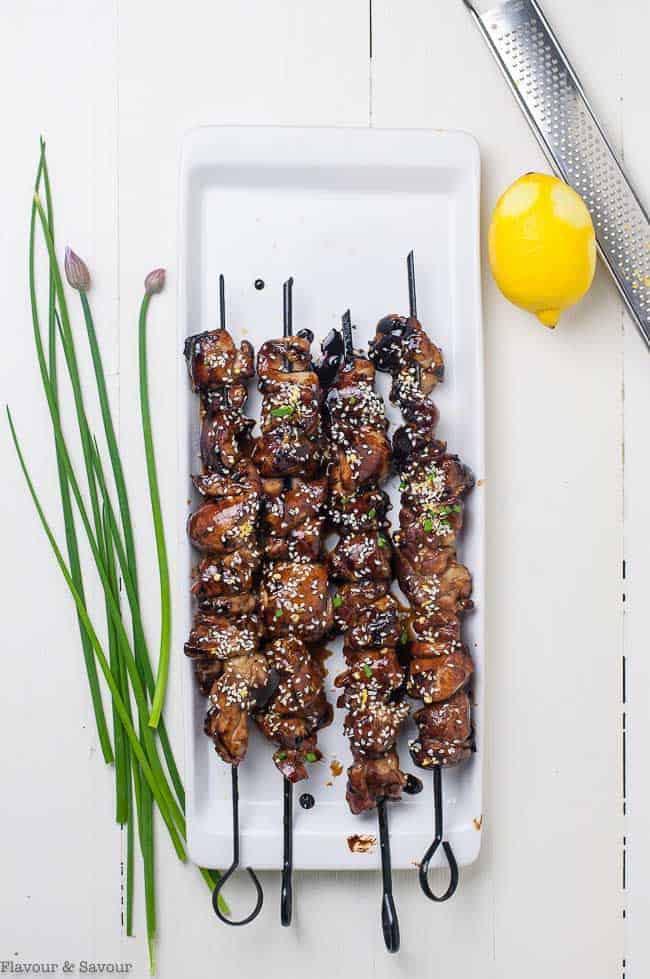 Japanese Chicken Yakitori Skewers on a white plate with fresh chives