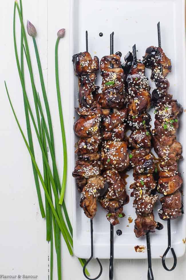 Easy Japanese Chicken Yakitori Skewers on a white serving tray with fresh chives and chive blossoms