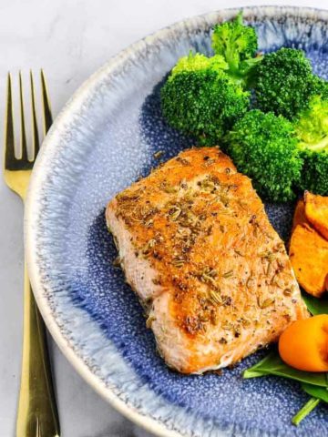 Fennel Crusted Salmon with broccoli on a blue stoneware plate