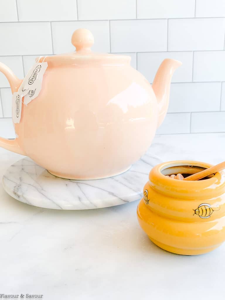 Green tea in a teapot with a honey pot beside it.