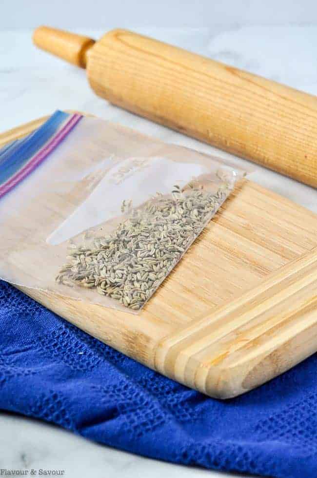 Grinding fennel seeds with a rolling pin in a resealable bag.