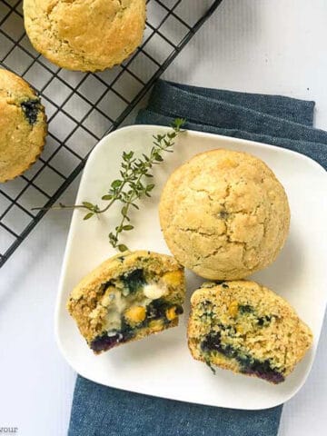 blueberry buttermilk cornbread muffins on a rack and on a plate
