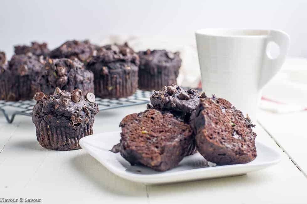Gluten-Free Double Chocolate Zucchini Muffins on a white plate with a cup of coffee.