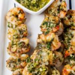 Grilled Chimichurri Shrimp Skewers on a platter with a bowl of Chimichurri Dipping Sauce