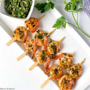 Appetizer size Chimichurri shrimp kabobs on a white platter.