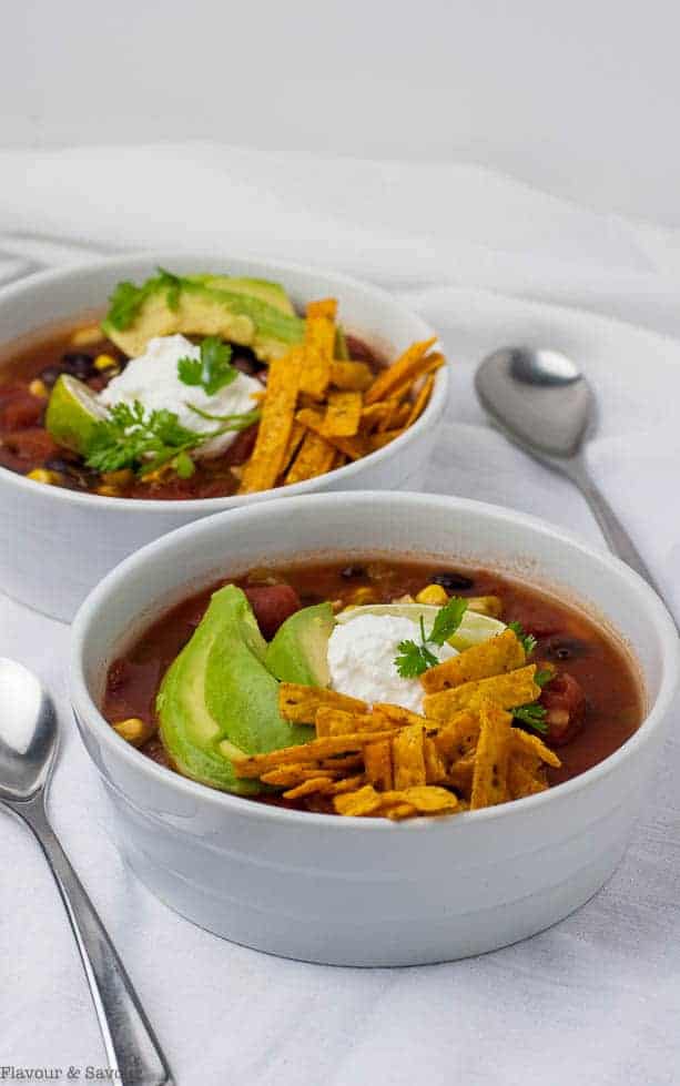 Slow Cooker vegan Texas Black Bean Soup garnished with avocado, lime and tortilla strips