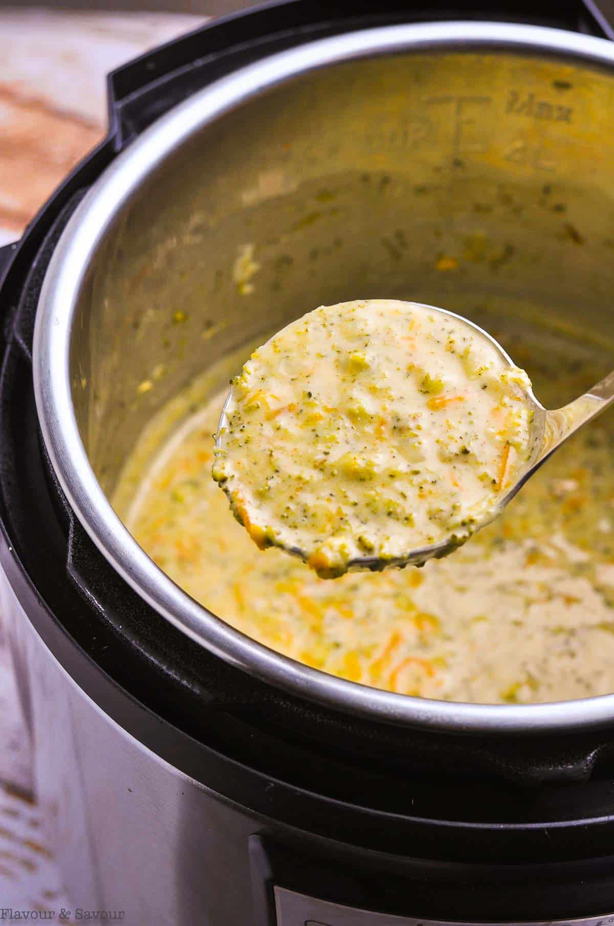A ladleful of Broccoli Cheddar Soup over an Instant Pot.