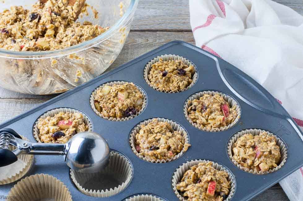 filling muffin cups with pumpkin oatmeal muffin batter