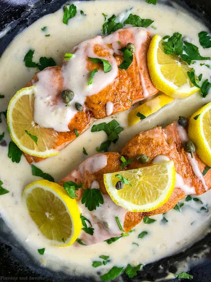 Close up view of 30 Minute Creamy Lemon Salmon PIccata garnished with lemon slices and parsley