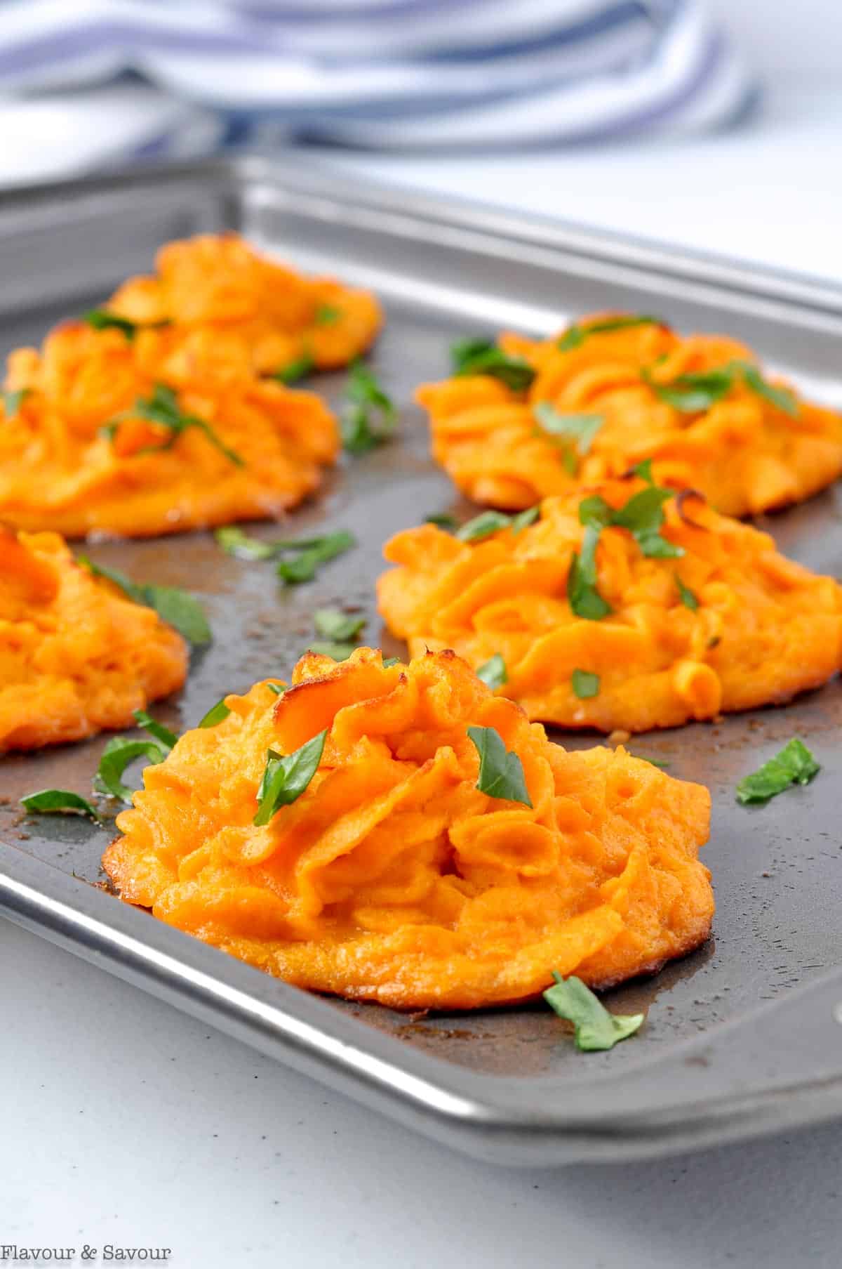 Duchess sweet potato mounds on a baking sheet garnished with parsley