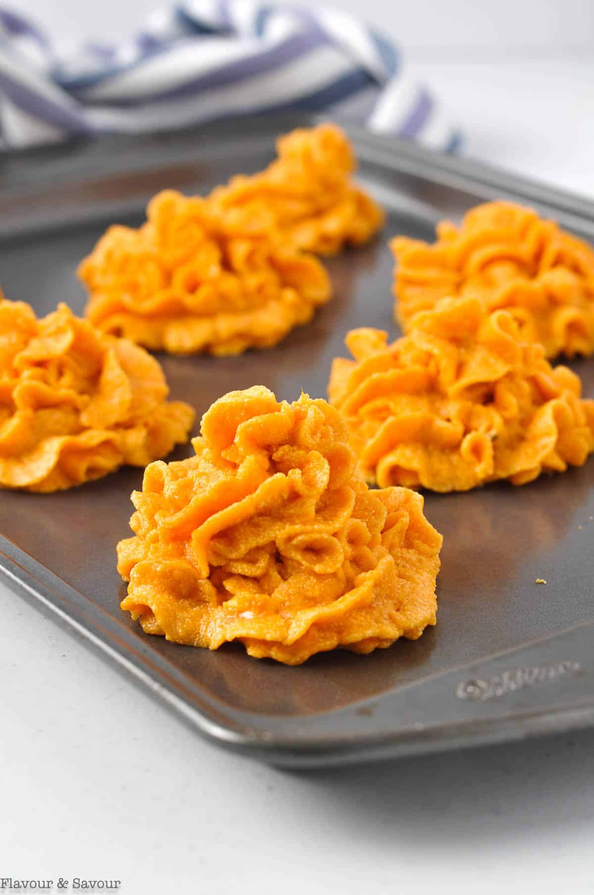 Piped mounds of sweet potatoes on a baking sheet