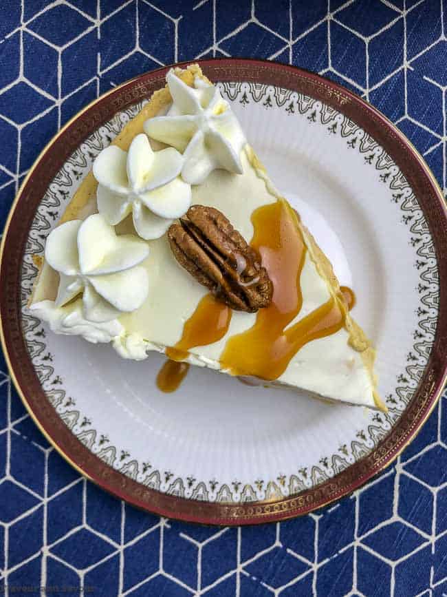 a wedge of Creamy Gluten-Free Pumpkin Cheesecake with caramel sauce